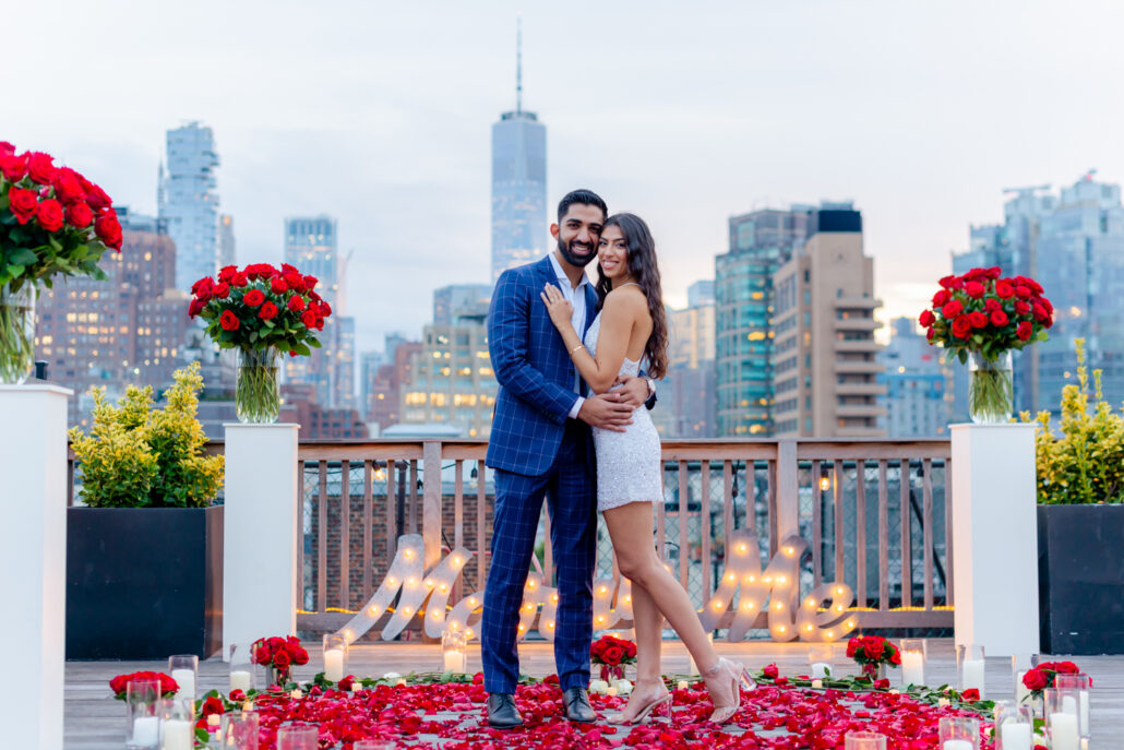 Luxury NYC rooftop proposal with a steel marry me sign and red rose and rose petals