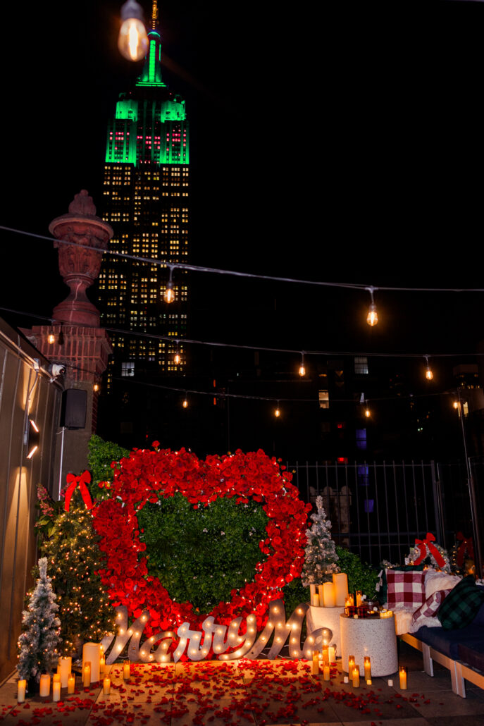 NYC Marriage Proposal Planing with Christmas Decorations on a Private Rooftop with a marry me sign and Empire views